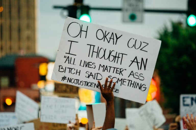 Faceless black person holding banner during demonstration on street