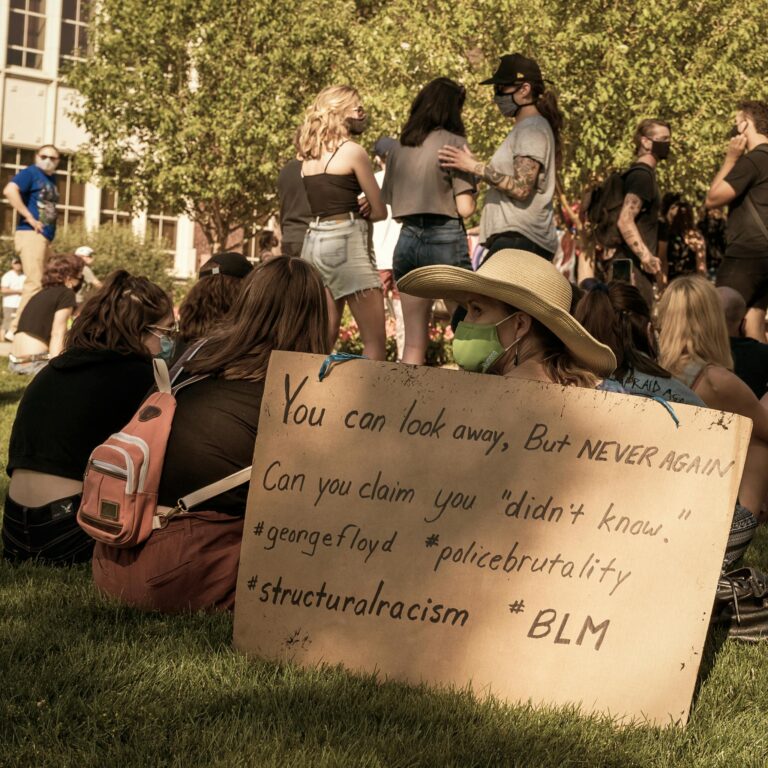 Group of friends protesting against racial discrimination in park with placard