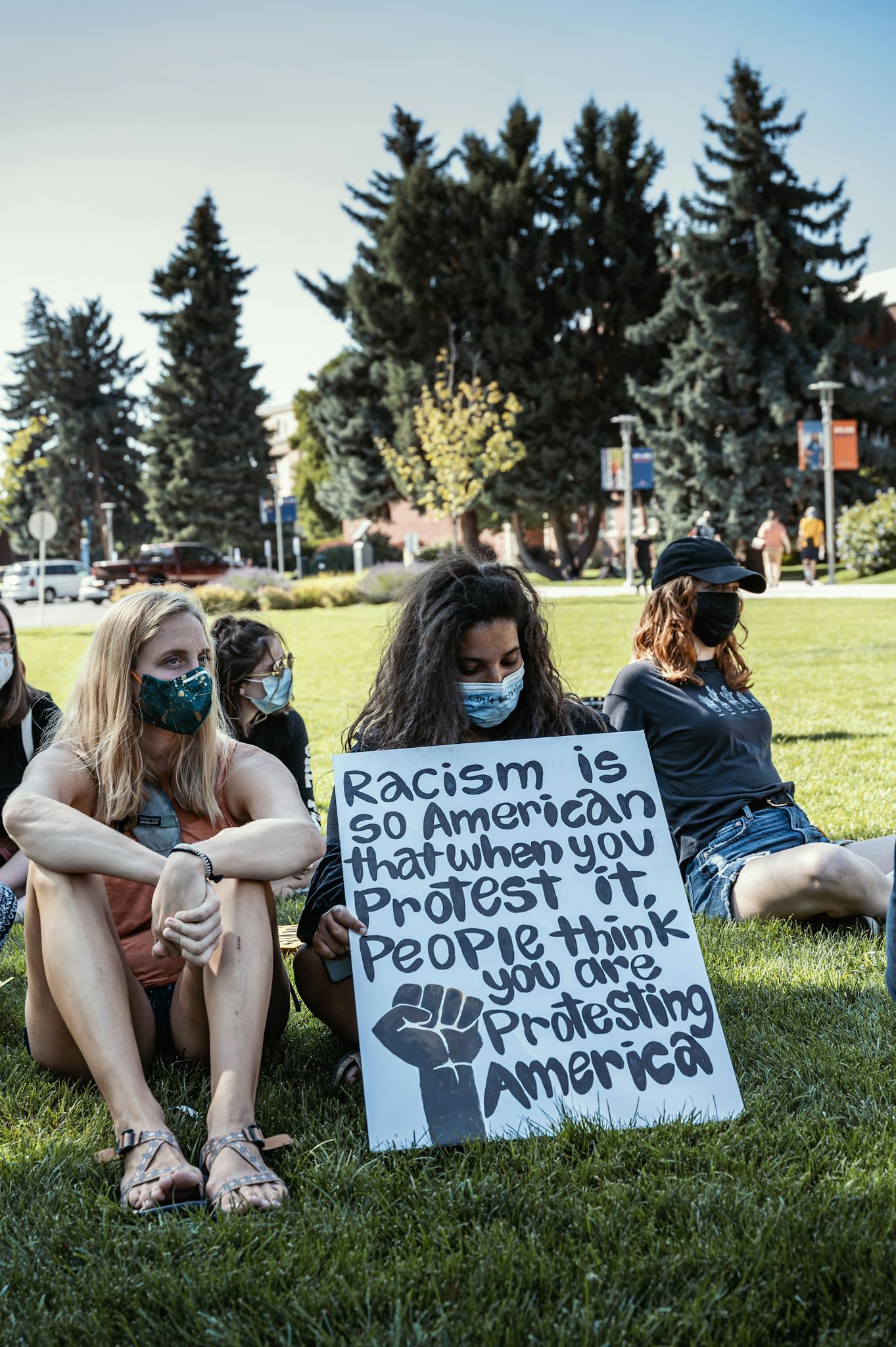 Group of women sitting on grass with sign